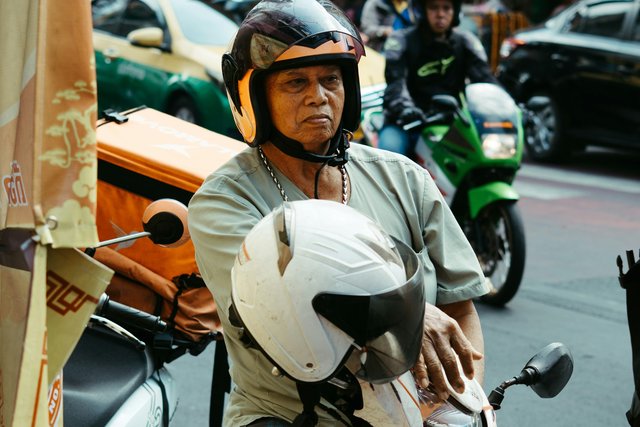 Scooter rider wearing a helmet on a road in Thailand