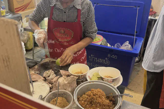Vendor preparing green papaya salad at a Bangkok street-food stall