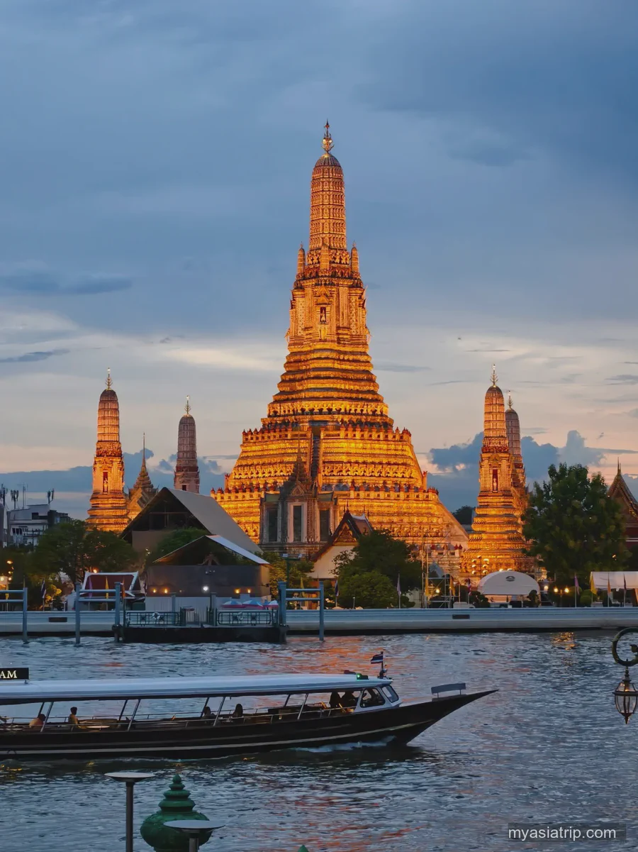 Wat Arun glowing beside the Chao Phraya River at dusk