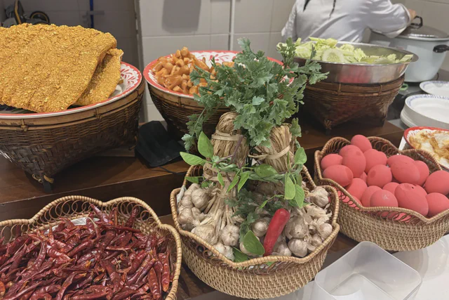 Baskets of dried chilies, garlic, herbs and eggs beside a kitchen counter