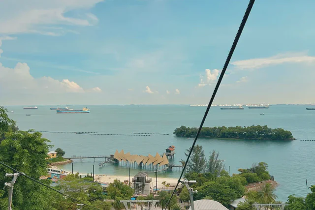 Cable cars crossing above Sentosa with the harbor in the distance