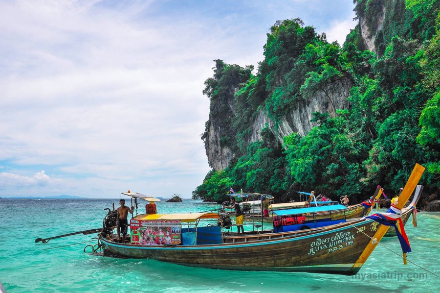 Traditional long-tail boat approaching a tropical Thai island