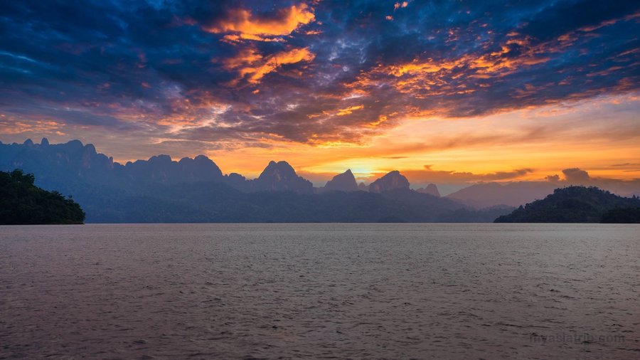 Mountain silhouettes and lake at sunset in Khao Sok, Thailand